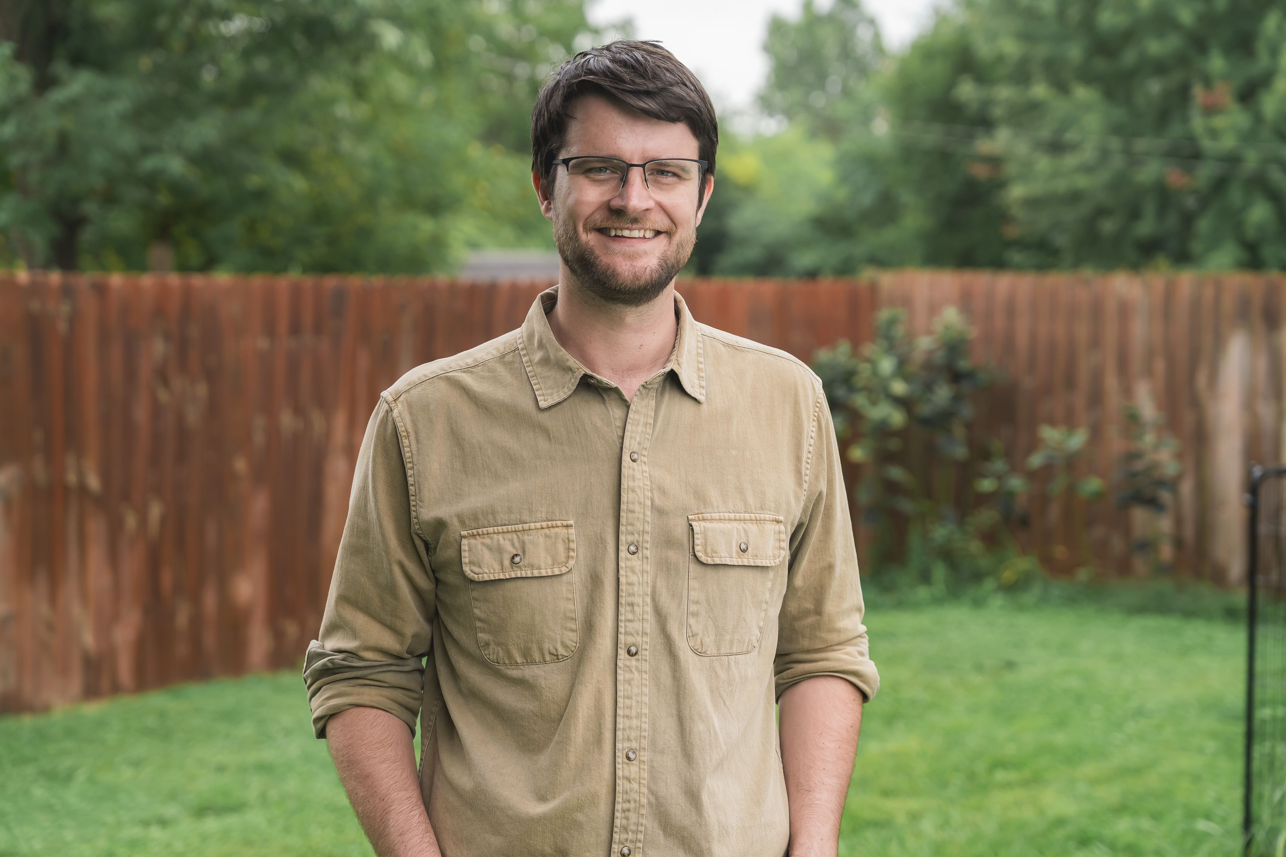 William Lawrence, Democratic candidate for Michigan's 7th Congressional District, smiling outdoors in a tan button-down shirt.